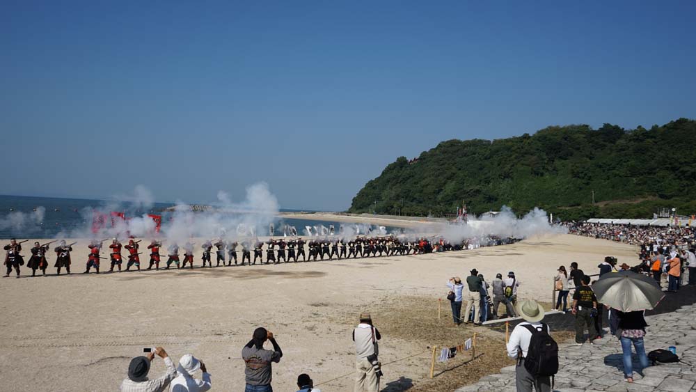 海を背に一斉射撃を行っている写真